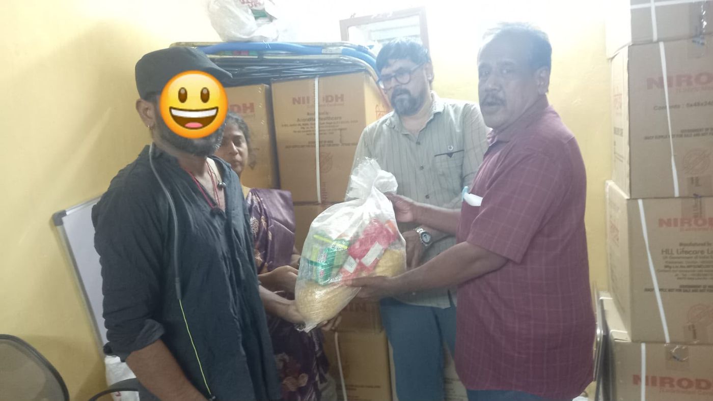 Staff handing a ration kit to a beneficiary, whose face is hidden