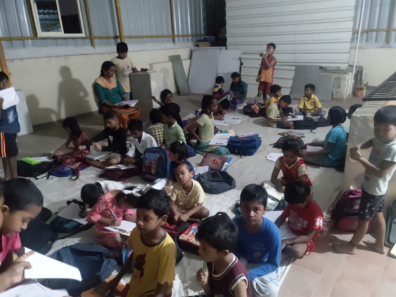Children seated in rows writing in notebooks