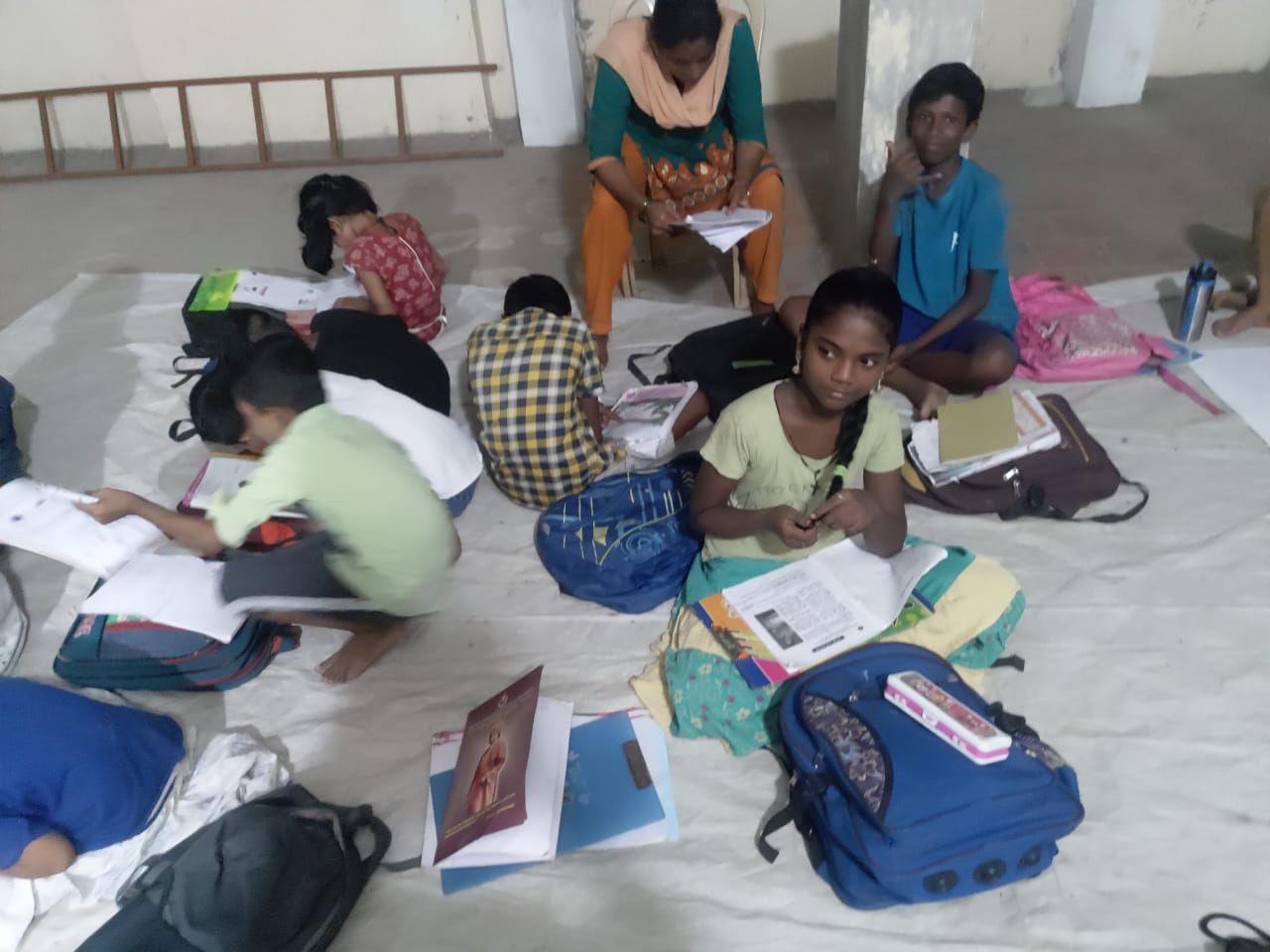 A volunteer teacher helping children with their books
