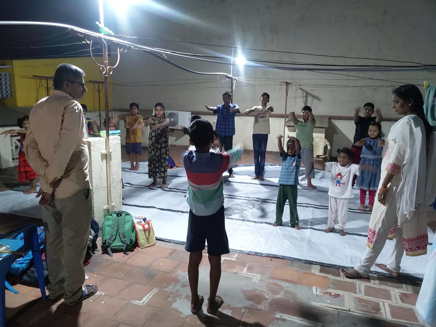 Children doing yoga on a rooftop with two volunteer teachers